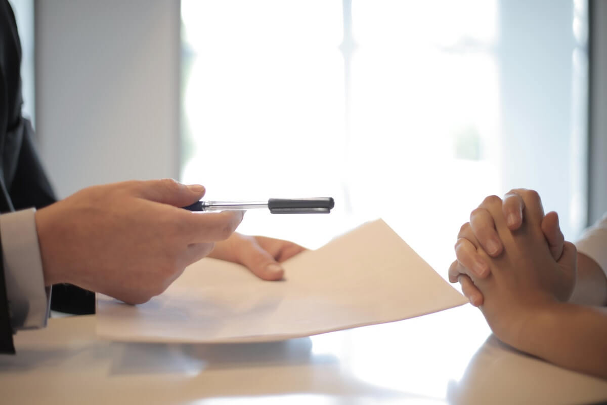 businessman handing a contract to a client to sign